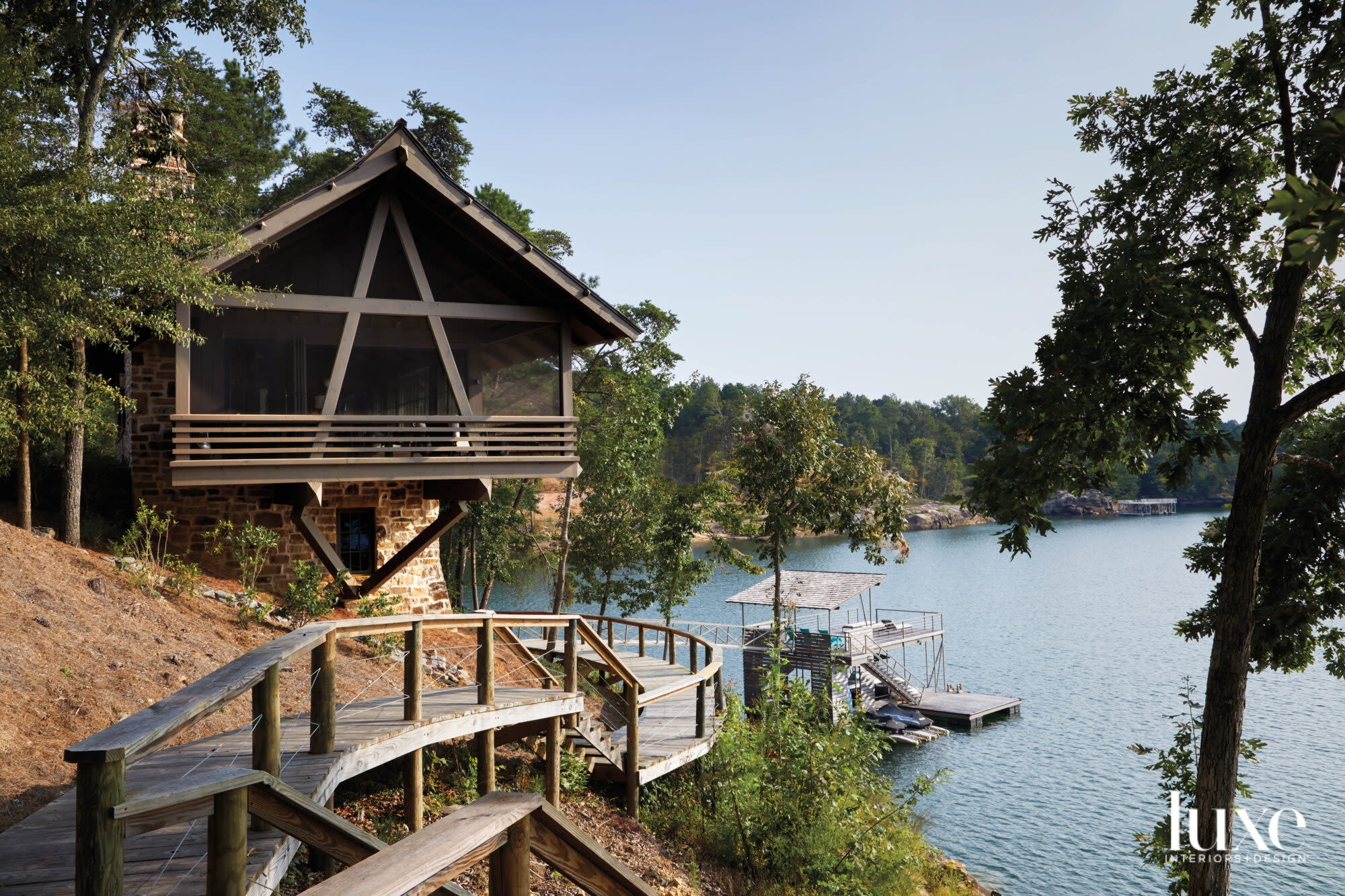 Cantilevered timber lake house set against placid lake with two-story dock