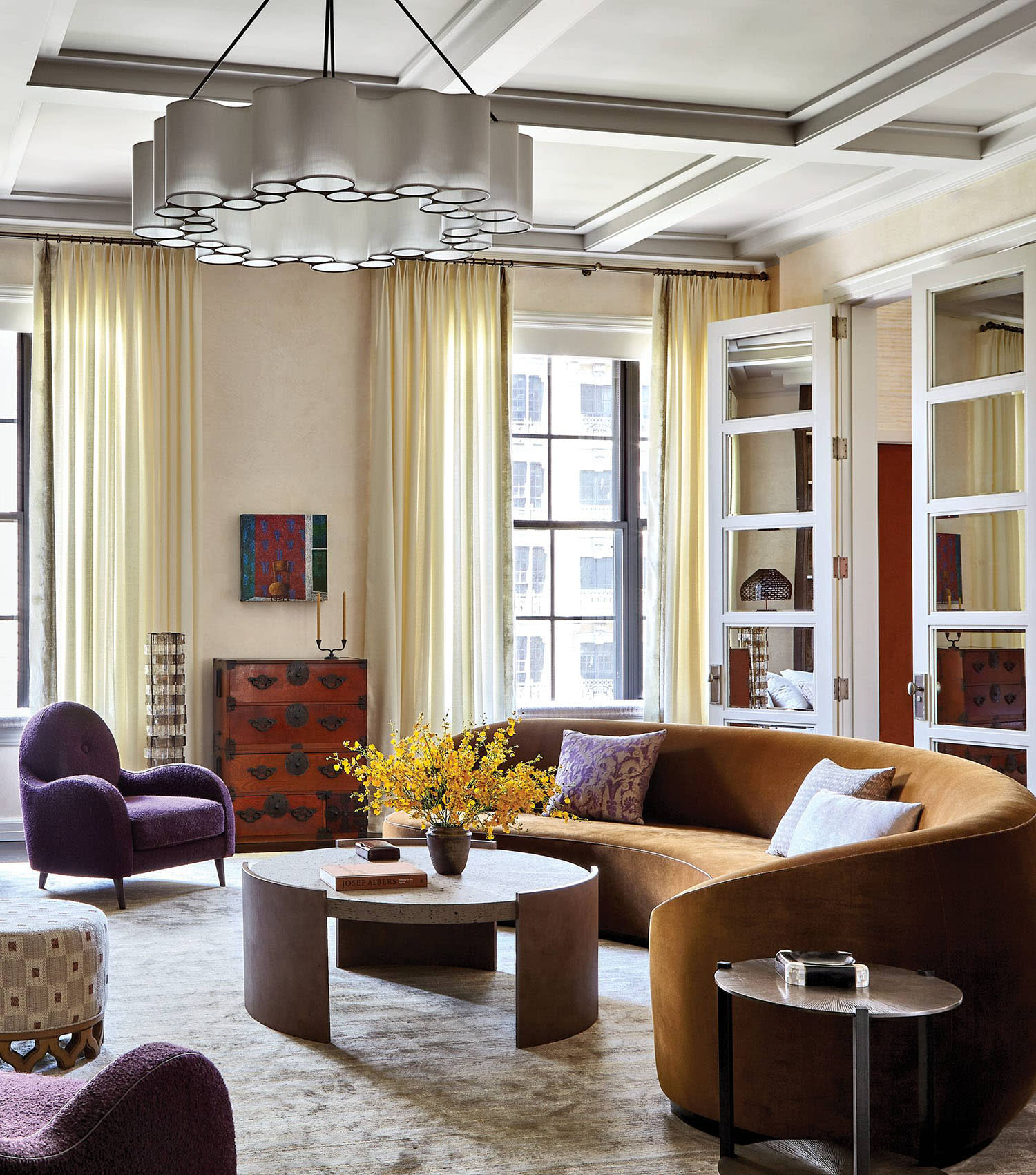 orange velvet couch beneath a sculptural chandelier in a modern living room