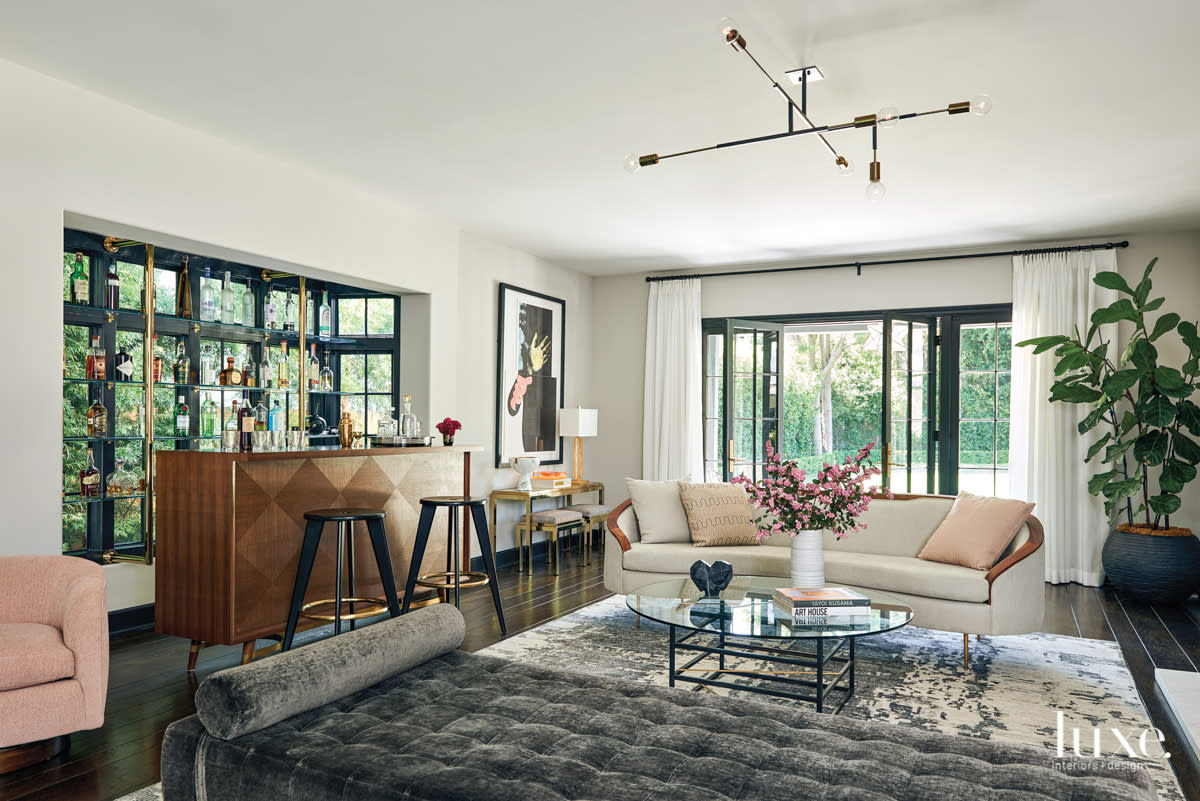 living room with a bar and bottles on shelves, a daybed and patterned rug