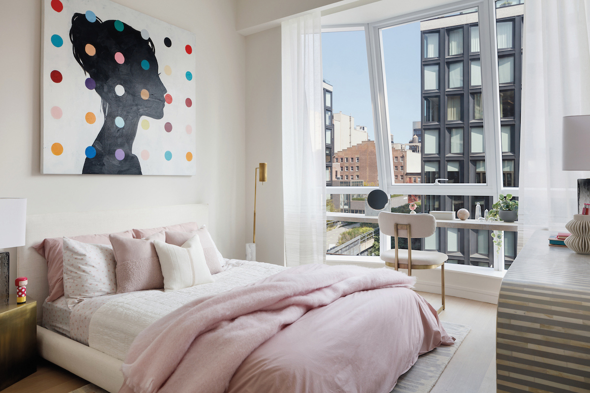 Bedroom with pink duvet, colorful artwork and large window overlooking New York City