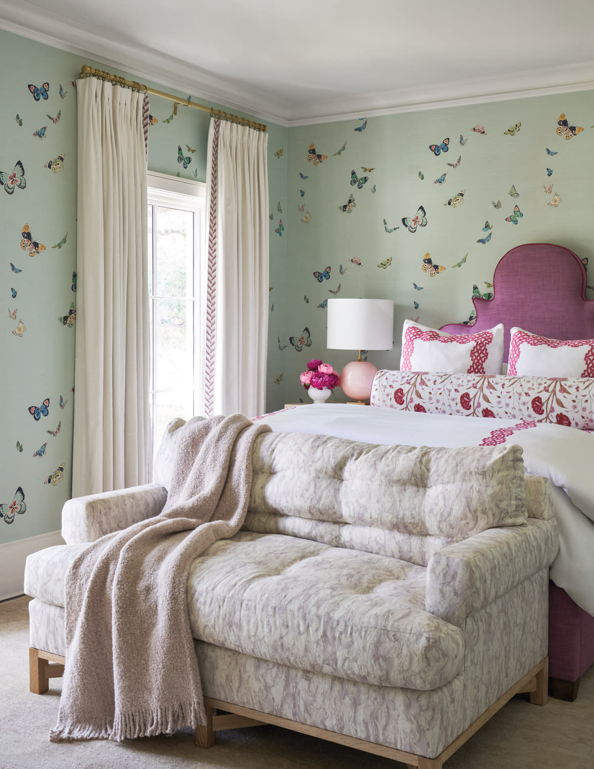 bedroom with butterfly wallpaper and furnishings in several colors and patterns