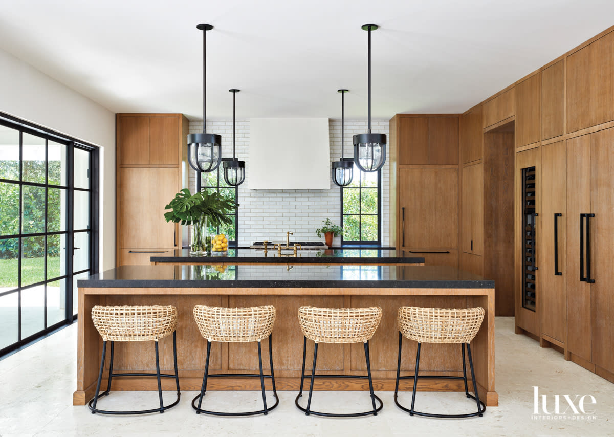 kitchen with cerused-oak cabinetry, wicker stools and iron lighting pendants