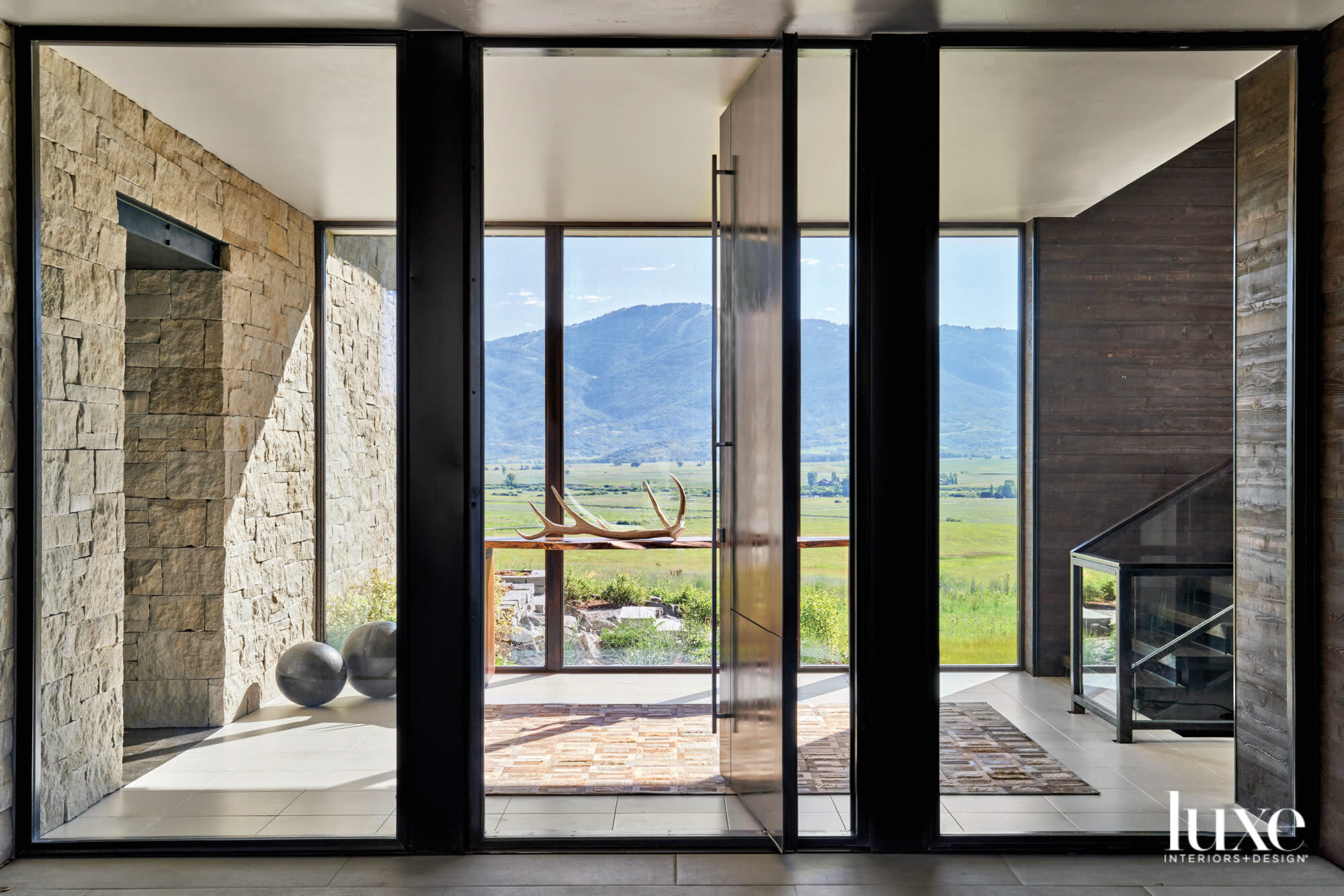 A mountainous view behind window walls and a dark Castlewood Door.