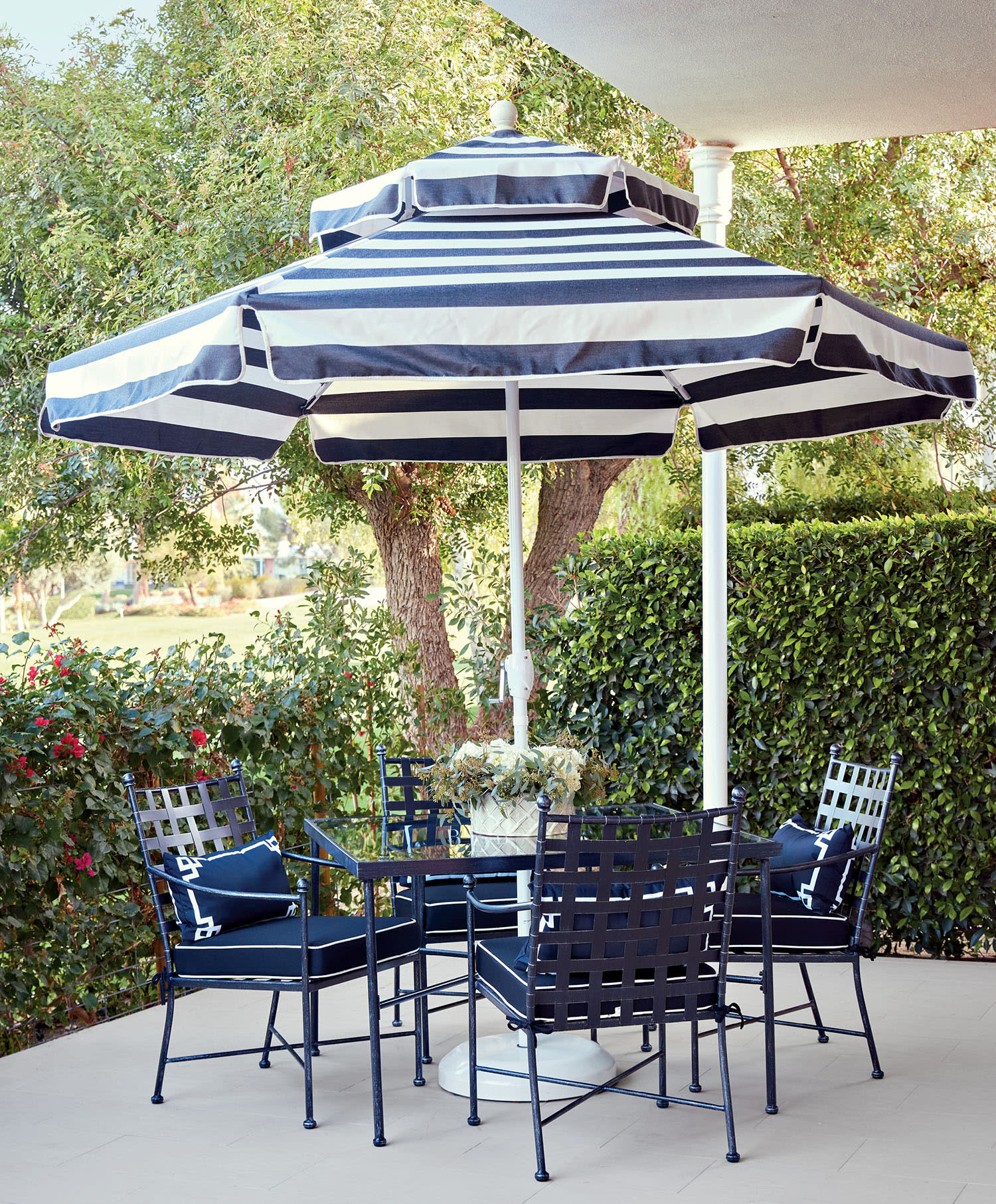 Patio setting with a black and white striped umbrella over a table and four matching metal chairs