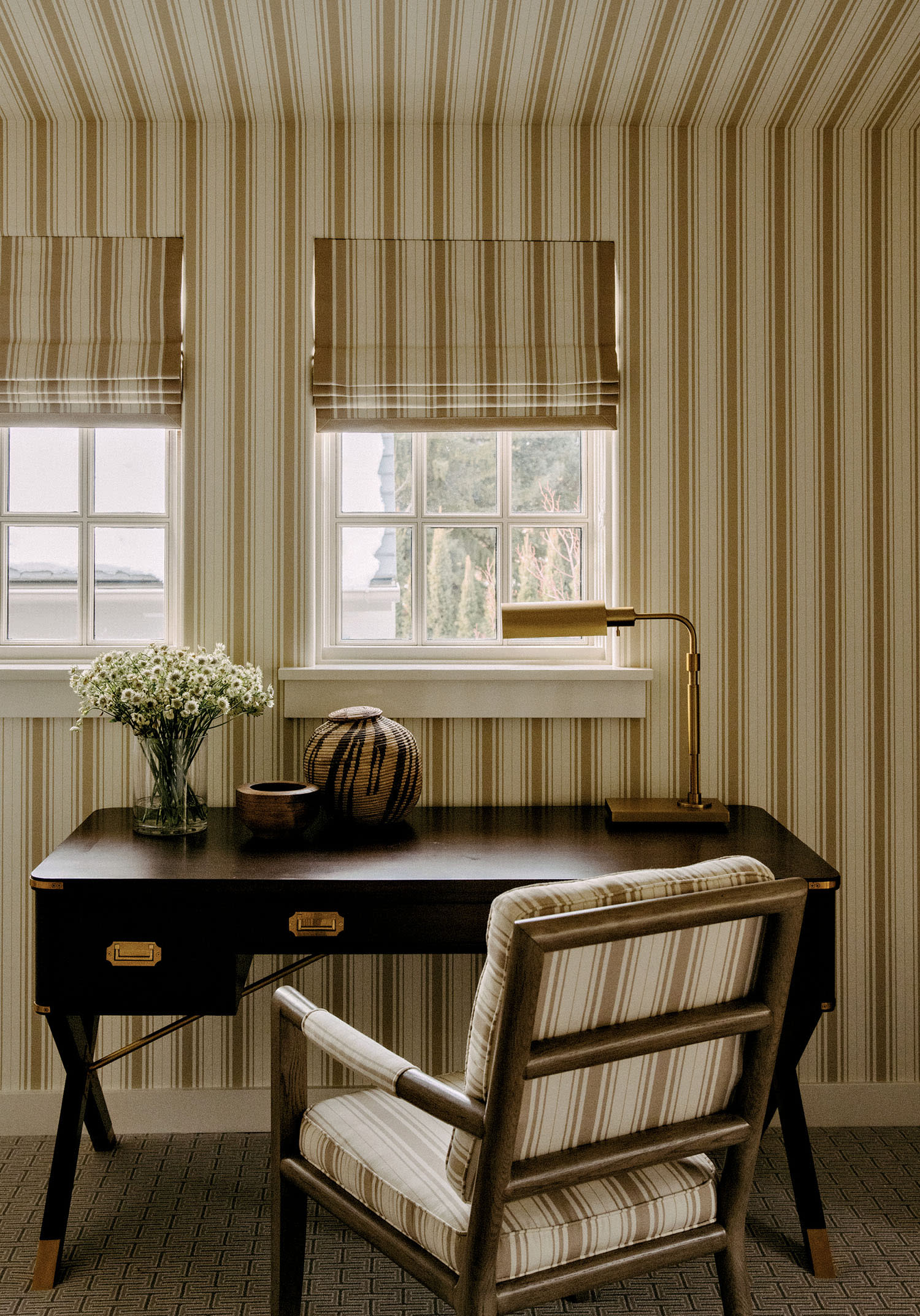Striped wallpaper. curtains and chair cushions in an office area with a dark wood desk.