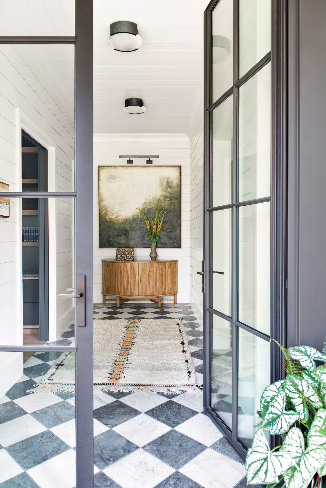 French doors opening to a foyer with checkerboard marble floors and wall art