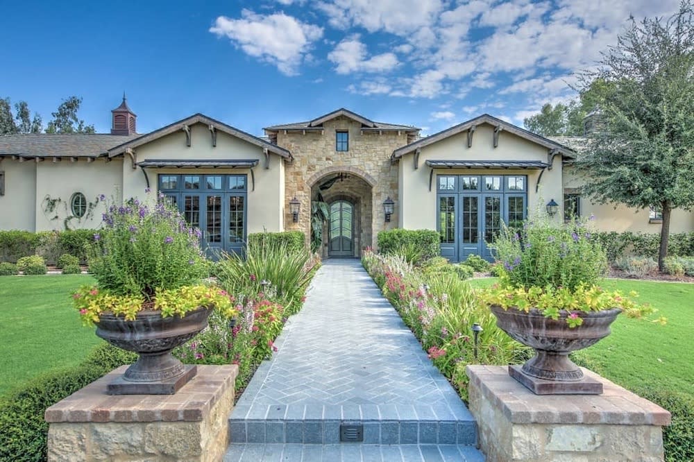 Front walkway with gray pavers and flowers lining both sides of the path