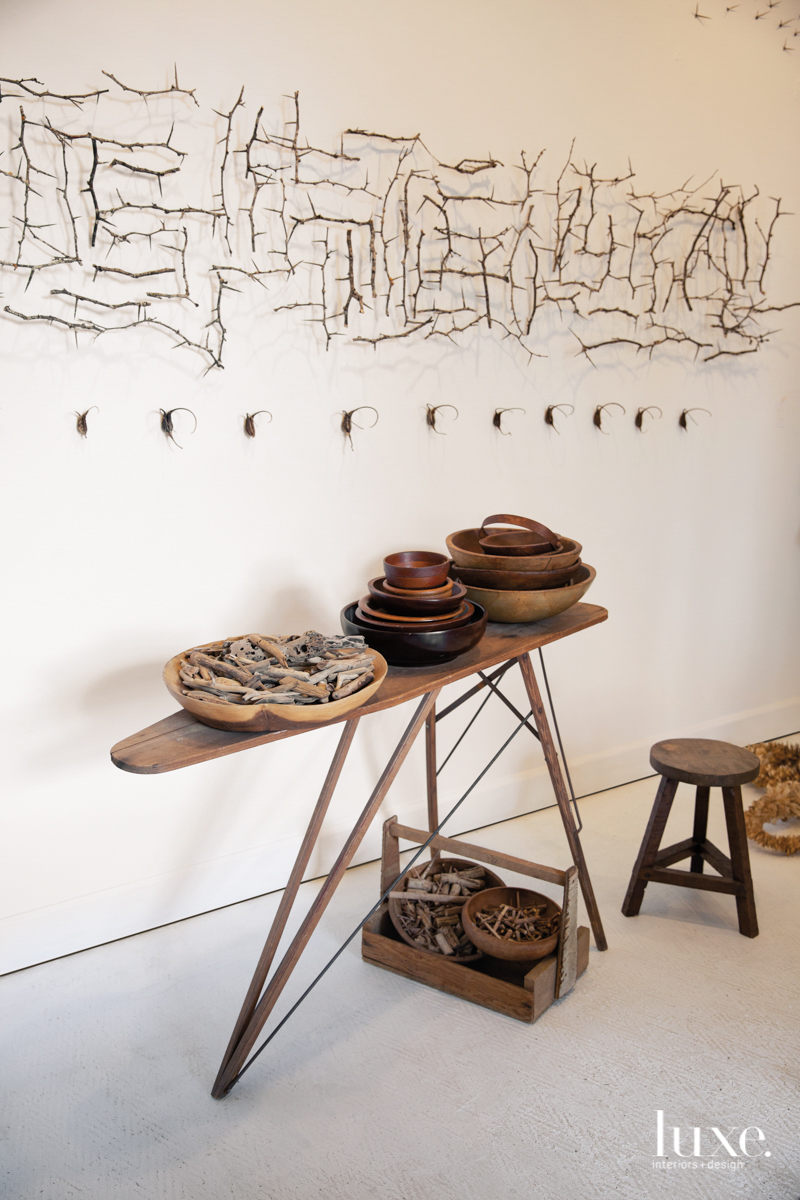 table with pots and branches of art on the wall