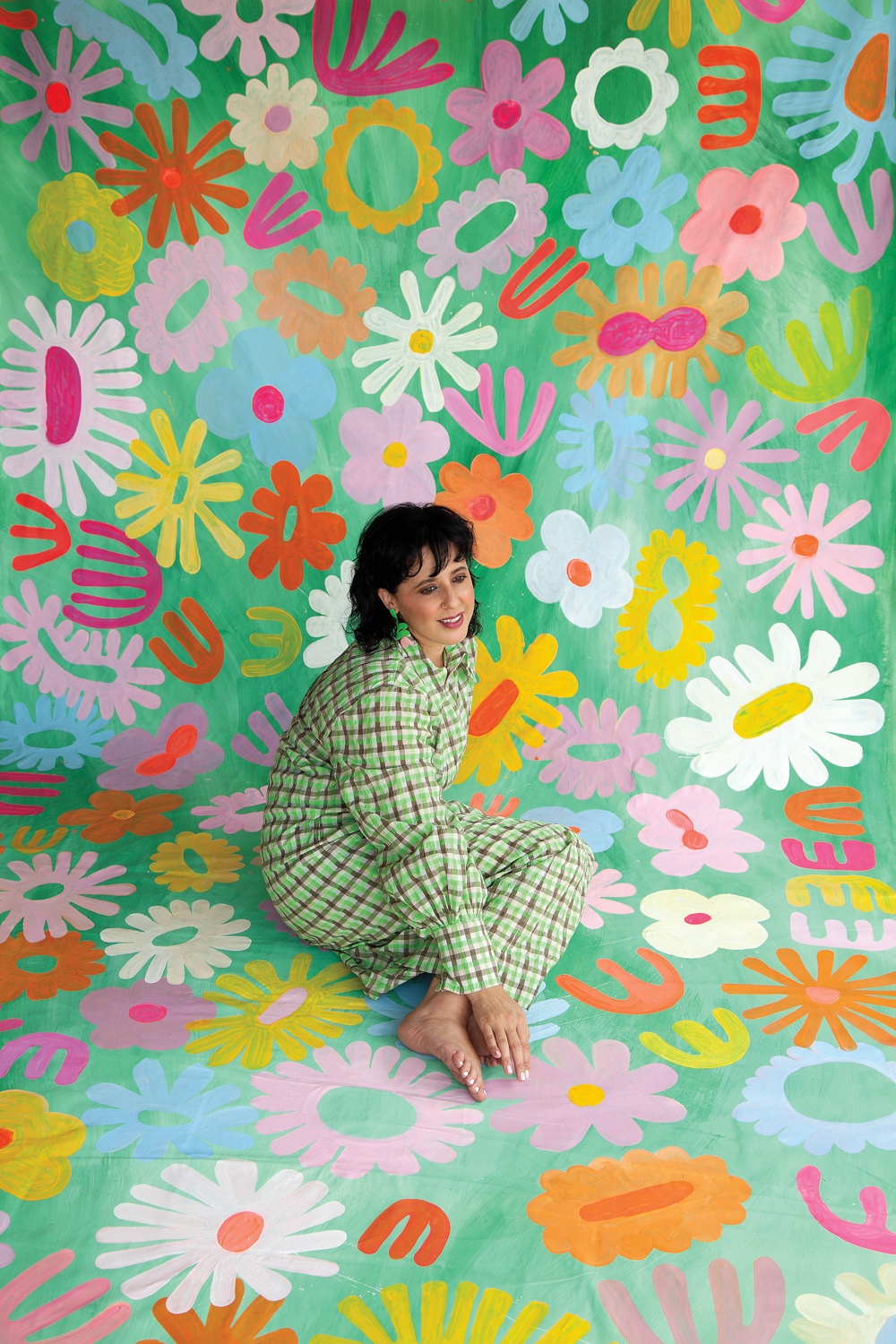 brunette women in plaid outfit sitting on a floral painted canvas