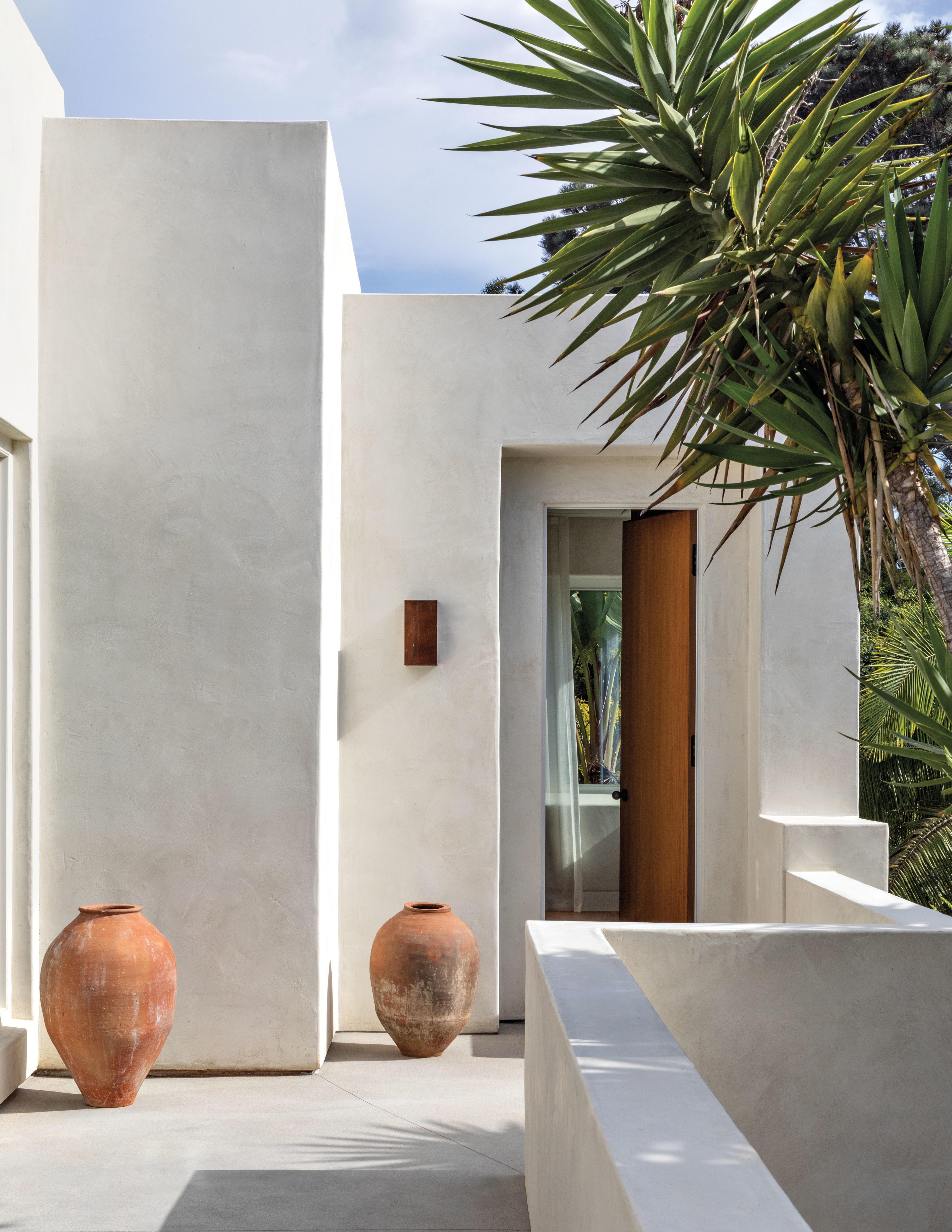 terra-cotta vessels line an outdoor walkway between the terrace and primary bedroom of this home