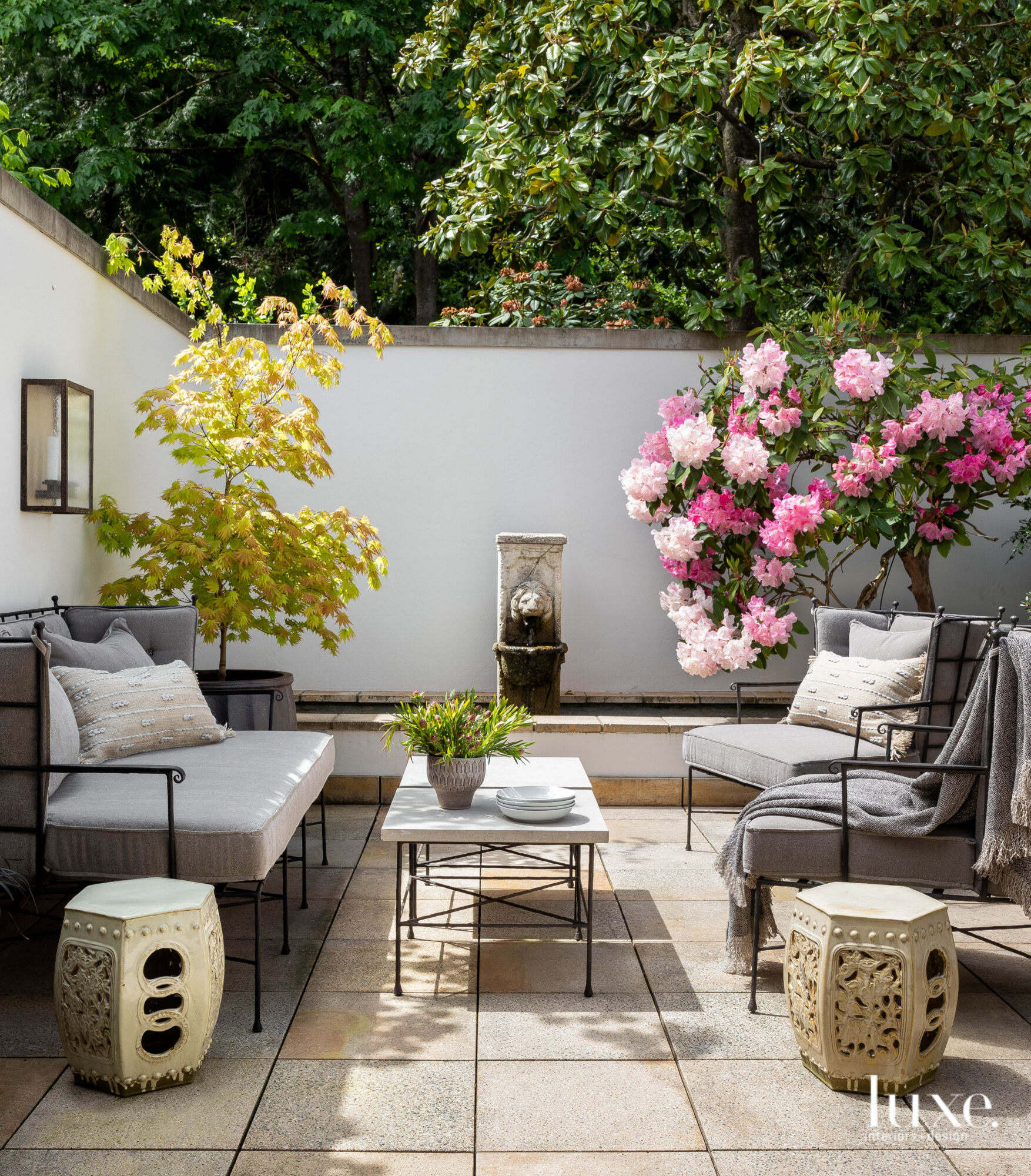 Outdoor seating area with sofa and a fountain in the background