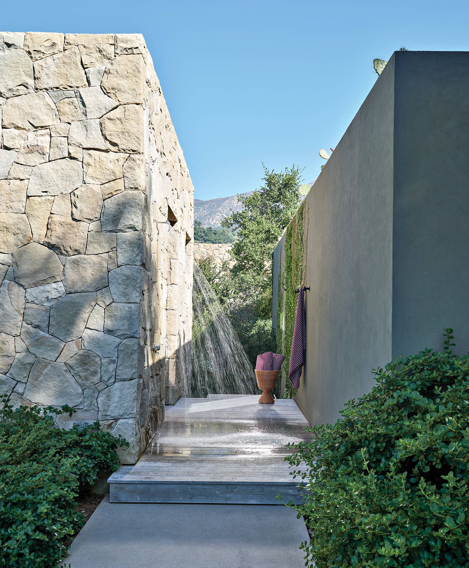 sandstone and tinted concrete exterior walls line the outdoor shower of a California home