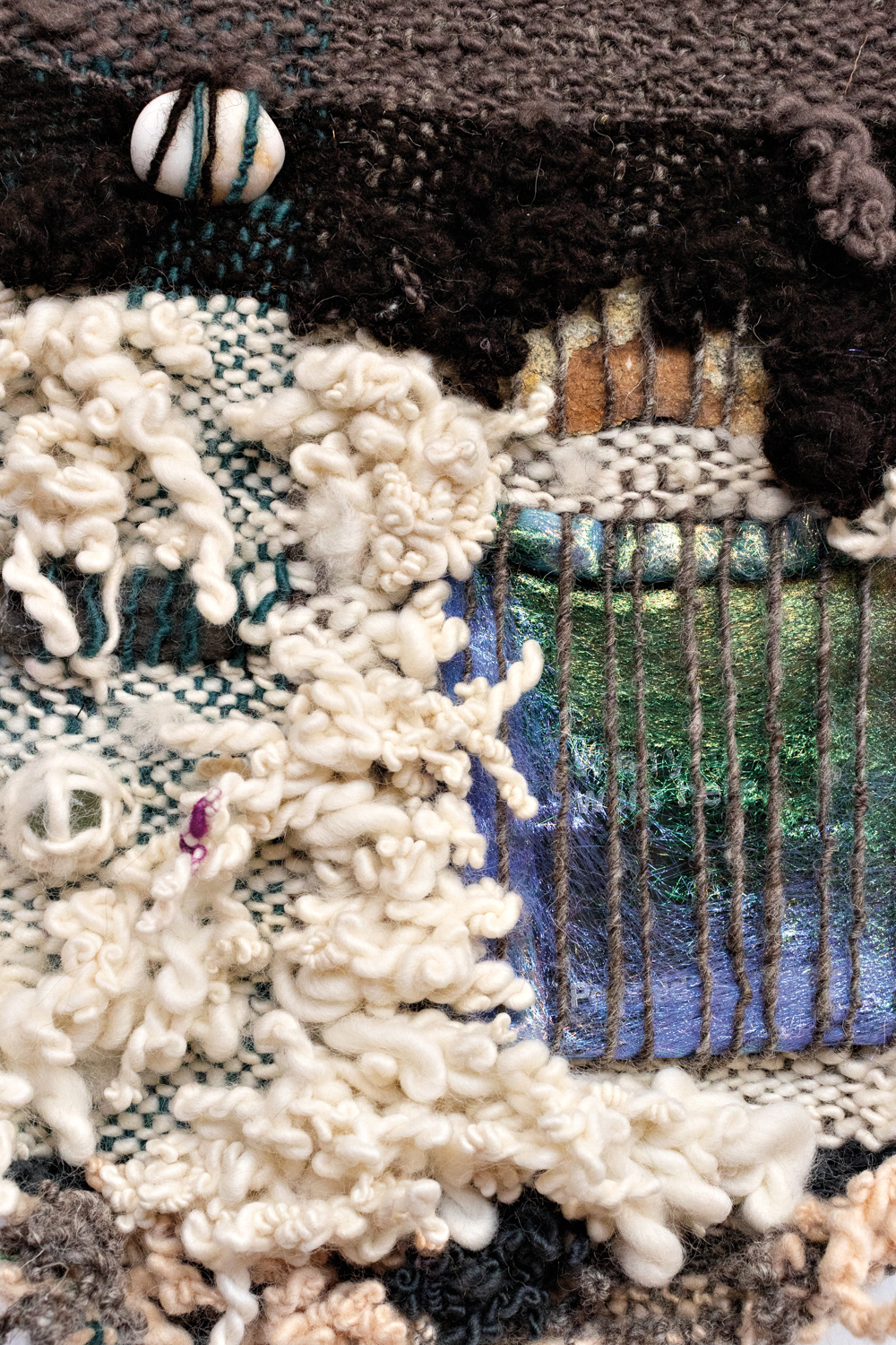 woven artwork featuring different textures and yarns in white, black, green and blue