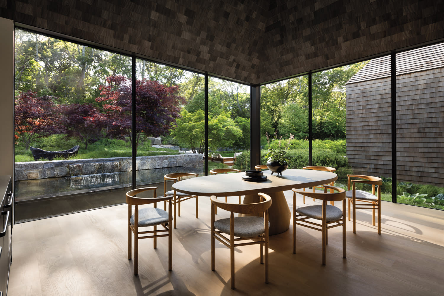 glass-walled dining room with views of a forest outside