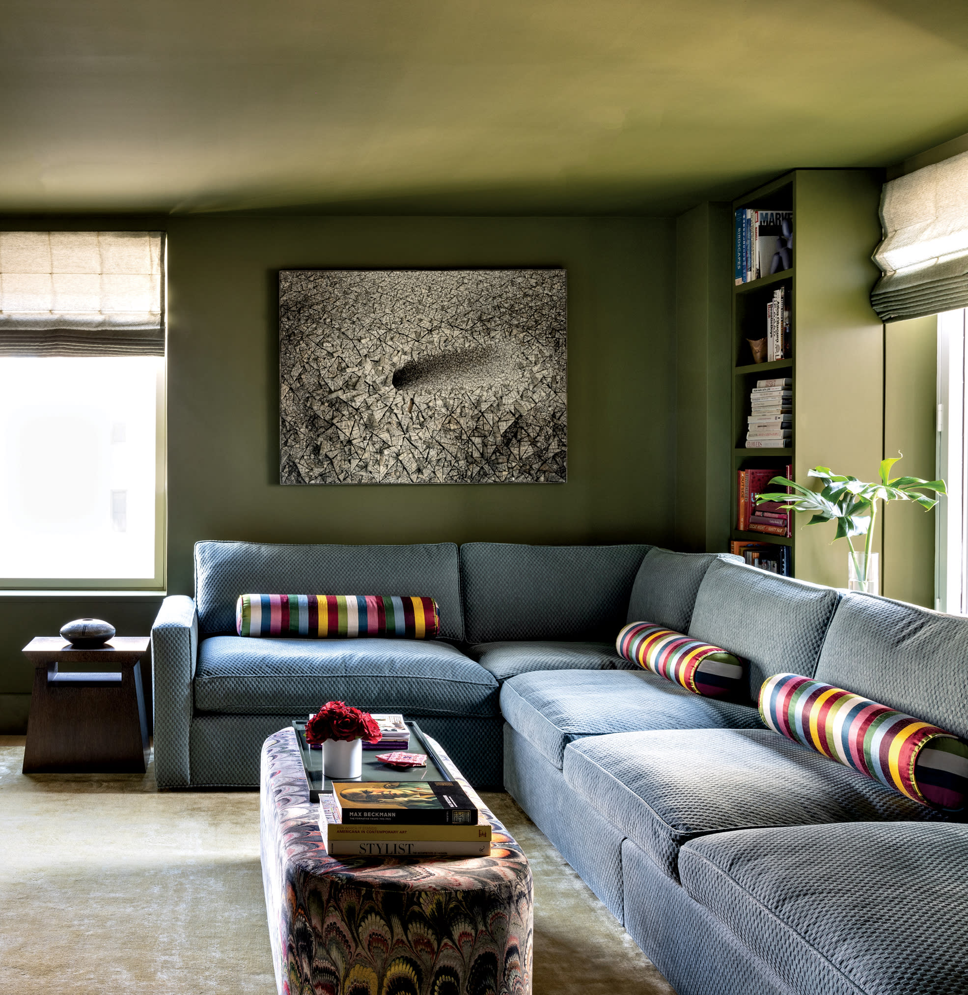 green den with a blue sofa topped with cylindrical rainbow-striped throw pillows