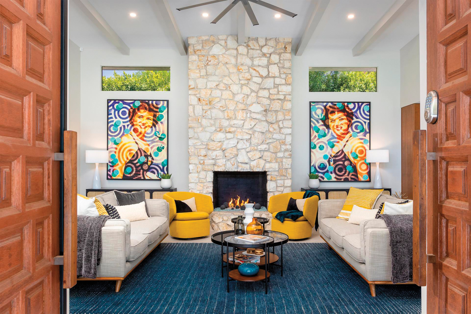 room with fireplace two yellow armchairs and colorful paintings