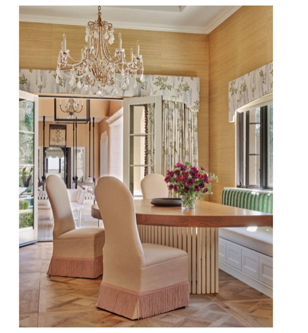 Breakfast nook with banquette seating, parque flooring, grass cloth wallpaper, custom drapery, skirted chairs and large, crystal chandelier.