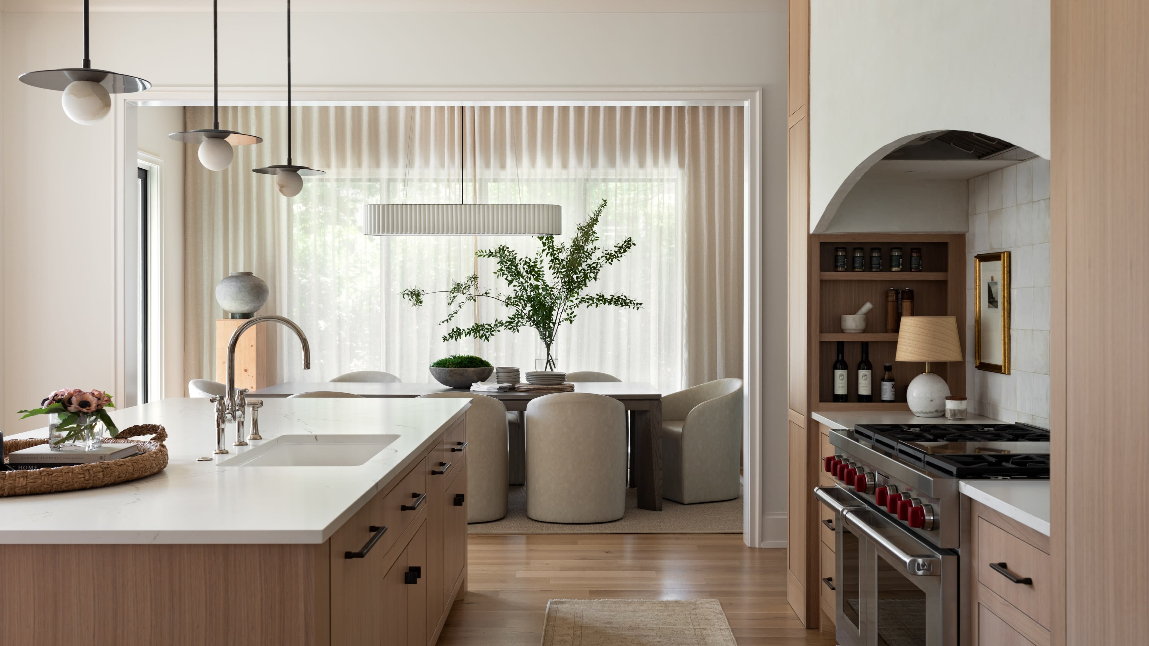 Modern kitchen with light wood cabinets, pendant lights, and a central island with a sink. 