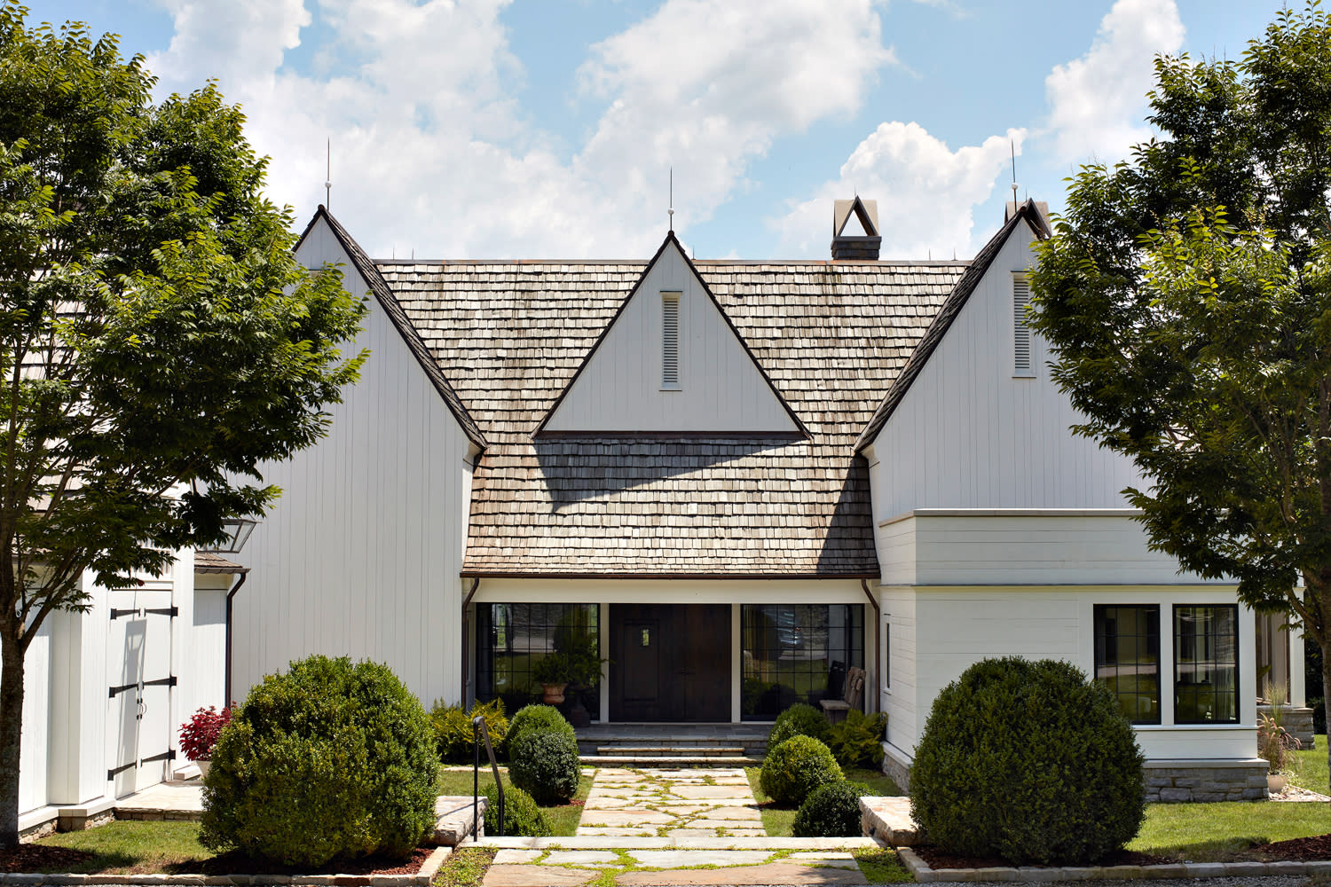 outside of white farmhouse surrounded by plants