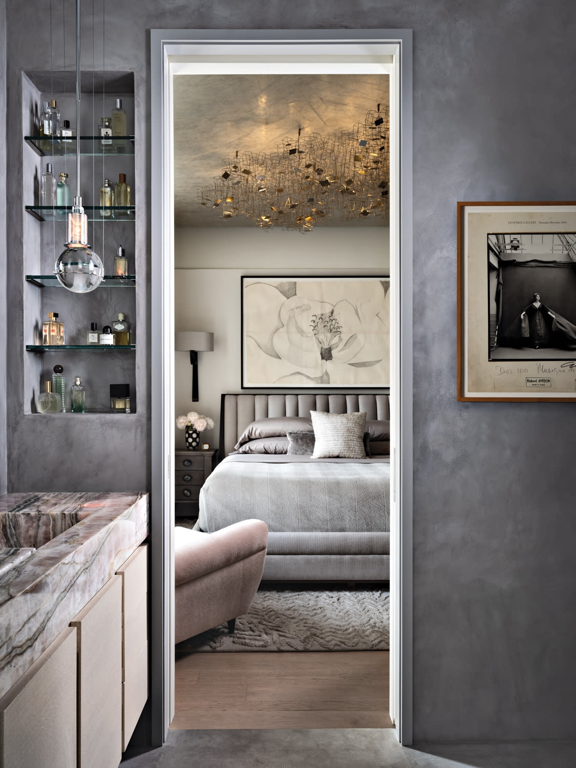 doorway of a luxury apartment with a pale pink stone sink and views of the bedroom beyond