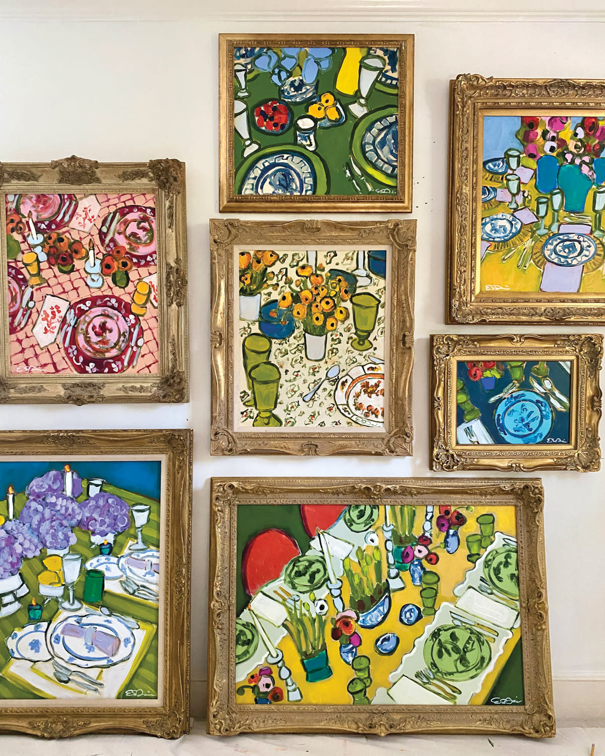 Several colorful artworks depicting table settings each in gold frames.