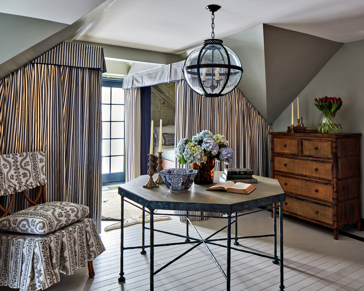 Cozy room with sloped ceiling, striped curtains, and a round glass pendant light.