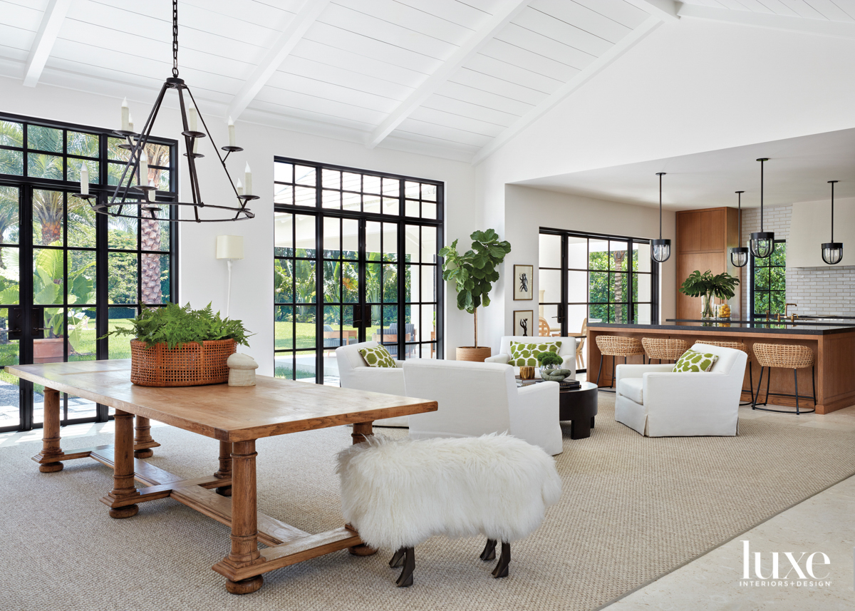 airy great room with large wood library table, iron chandelier, sheep-like stool and sitting area