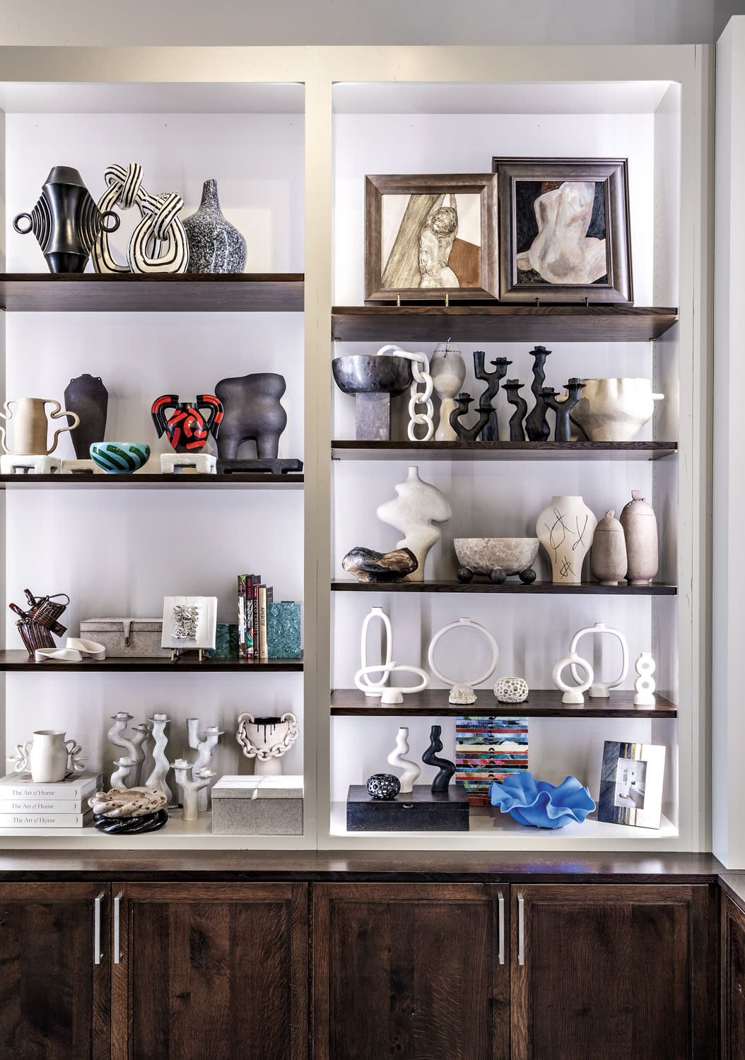 Shelves filled with black and white vessels, framed artwork and sculpture.