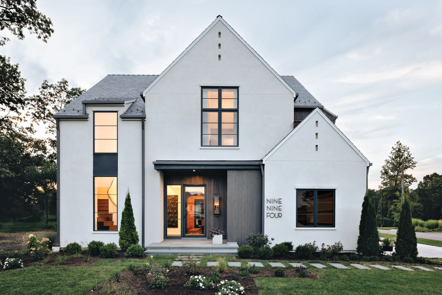 white modern home exterior lit up at evening