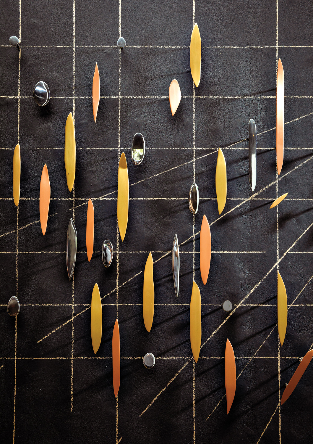 multiple yellow and orange metal pieces on a black wall