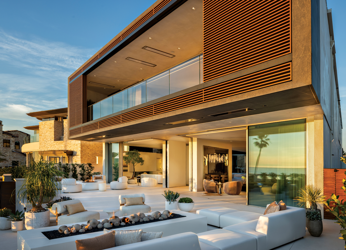 Exterior street view of a modern coastal home with retractable windows open, blending indoor and outdoor living with ocean views.