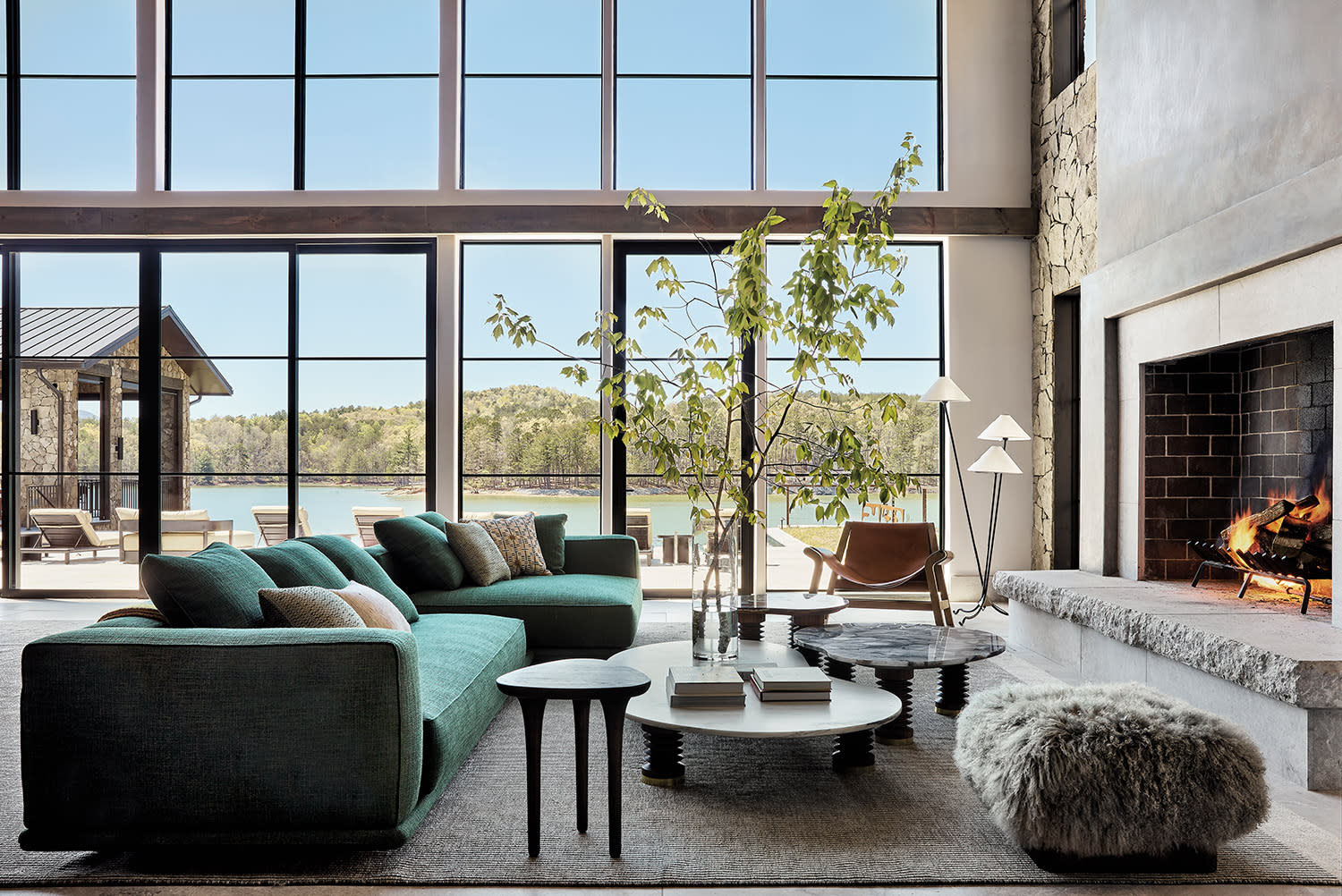 living room fireplace area with a green sectional and a shearling ottoman