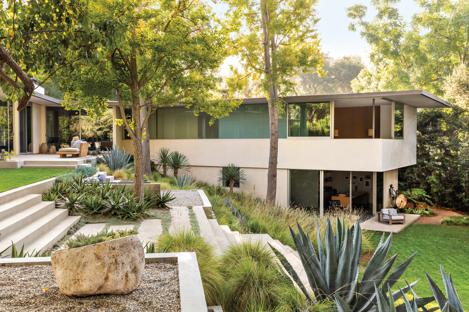 Midcentury modern house with stairs flanked by a rolling hillside garden