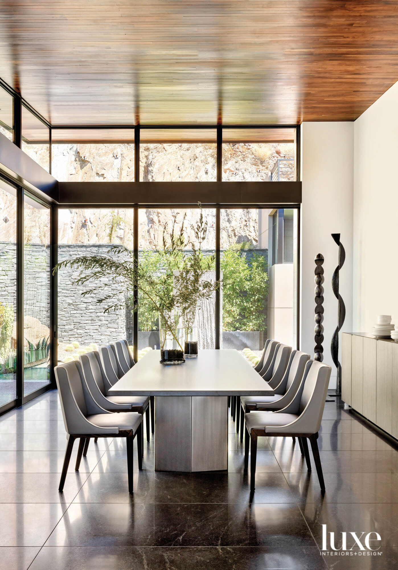 A dining room with stone floors that looks out on to a garden.