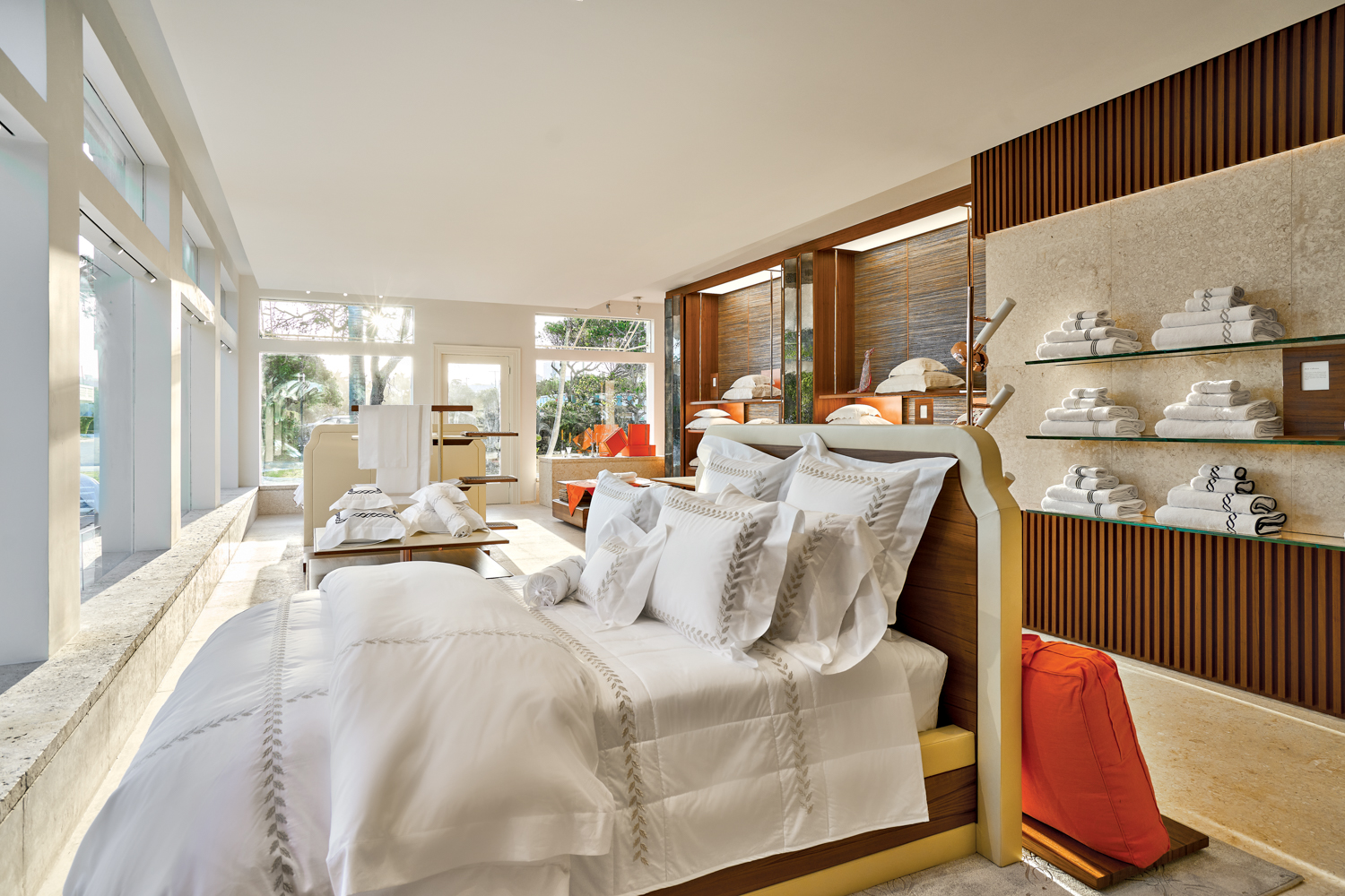 showroom with made bed, shelves holding linen and towels