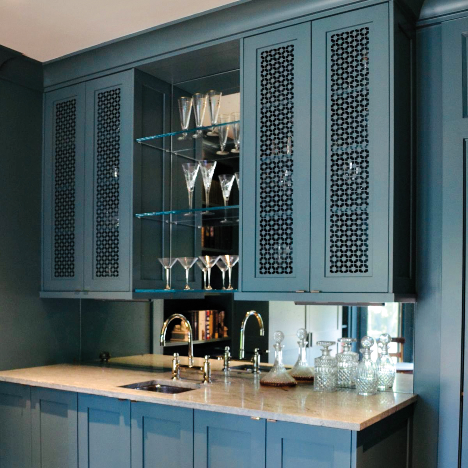 blue cabinetry insert with open shelving in the center holding drink glasses