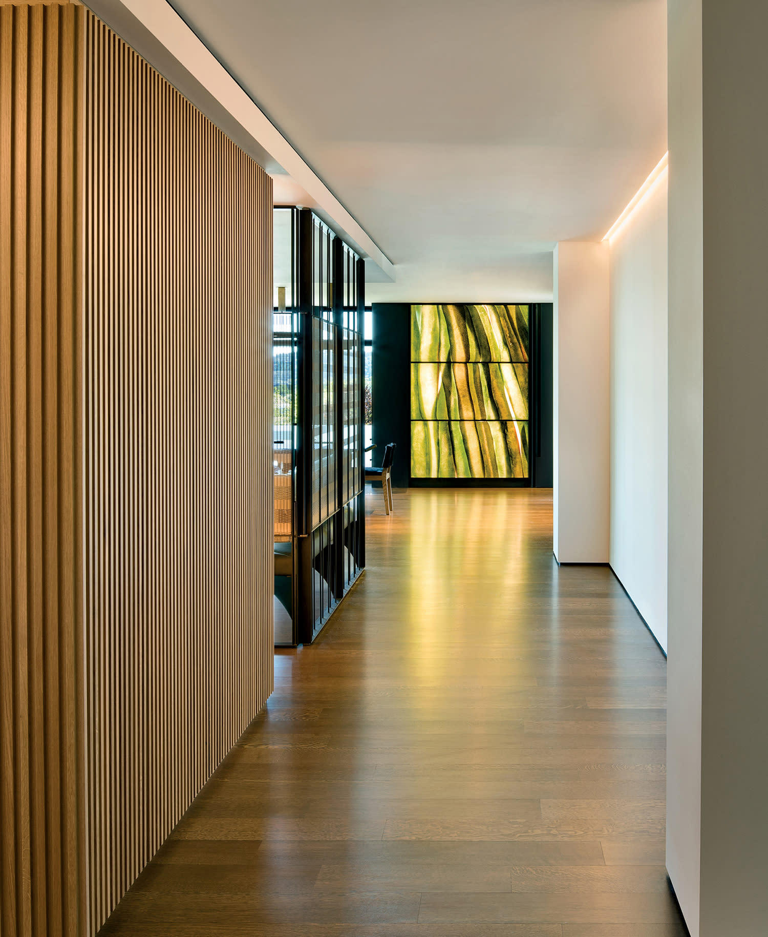 modern home entrance with a slatted wood panel and an abstract artwork down the hall