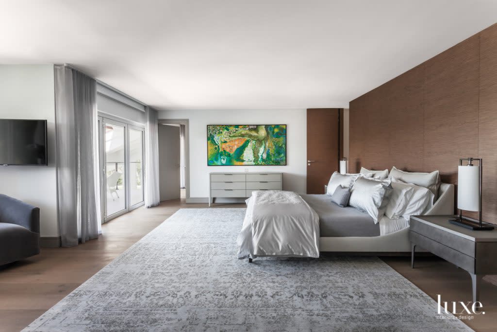 In the master bedroom, Artefacto's Greta chest and Mute nightstands join the brand's Brasilia bed, complemented by Frette linens. Bodor walnut paneling from Armazem accompanies a wall displaying Esmeralda, Malaquita y Jade by Zaida del Rio. The wool and silk rug is from Woven Art Specialist.