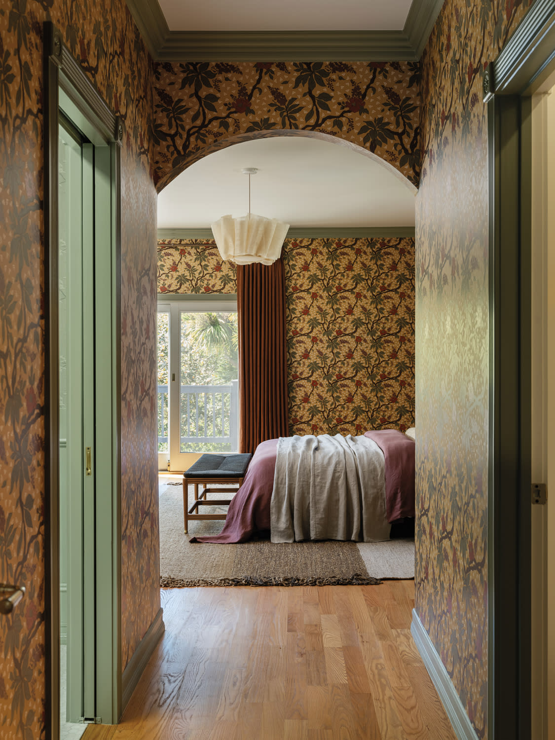 vintage-inspired floral wallpaper surrounds a bedroom and the hallway leading into it