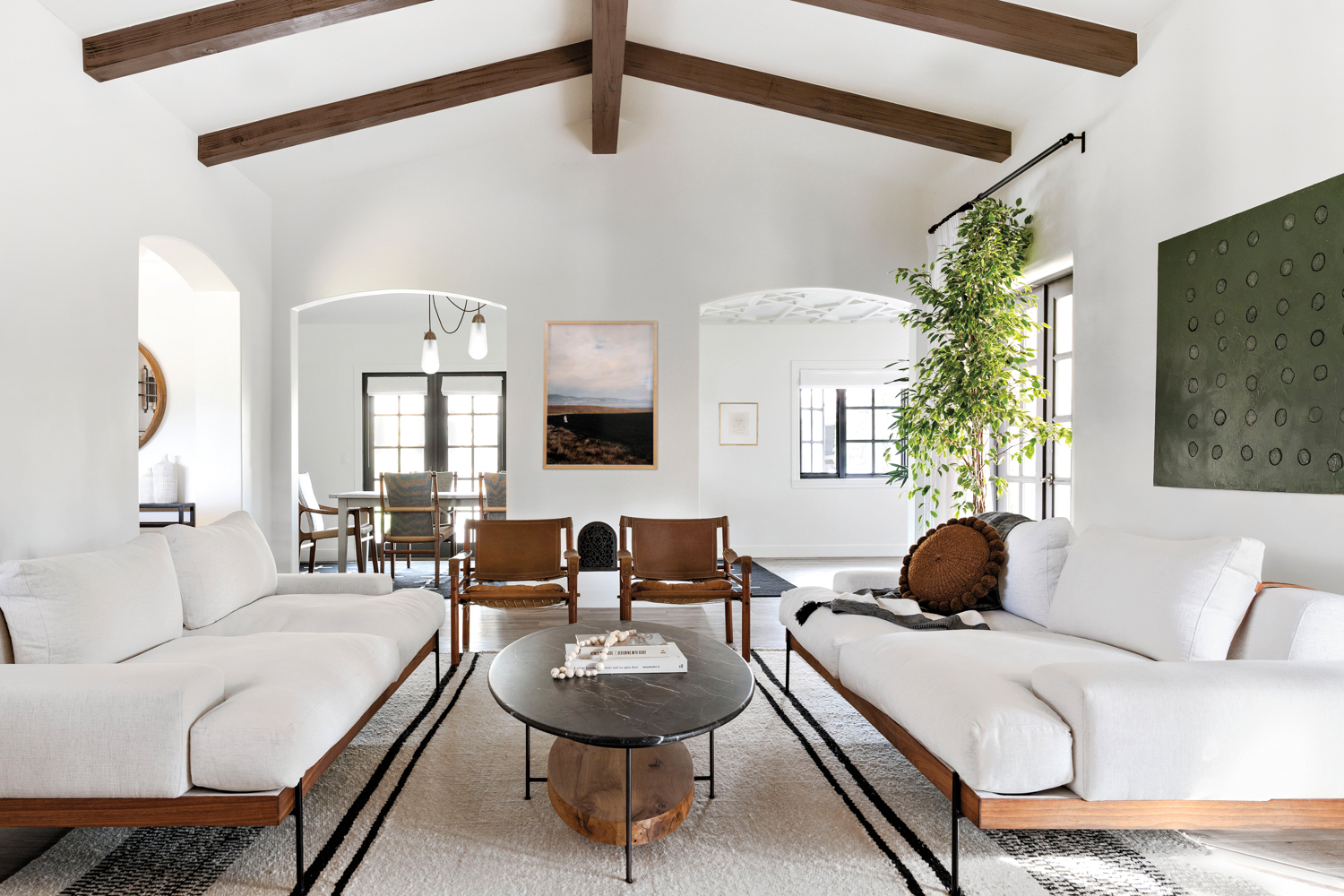 A white living room room with wood beams and a mix of white and wood furniture.