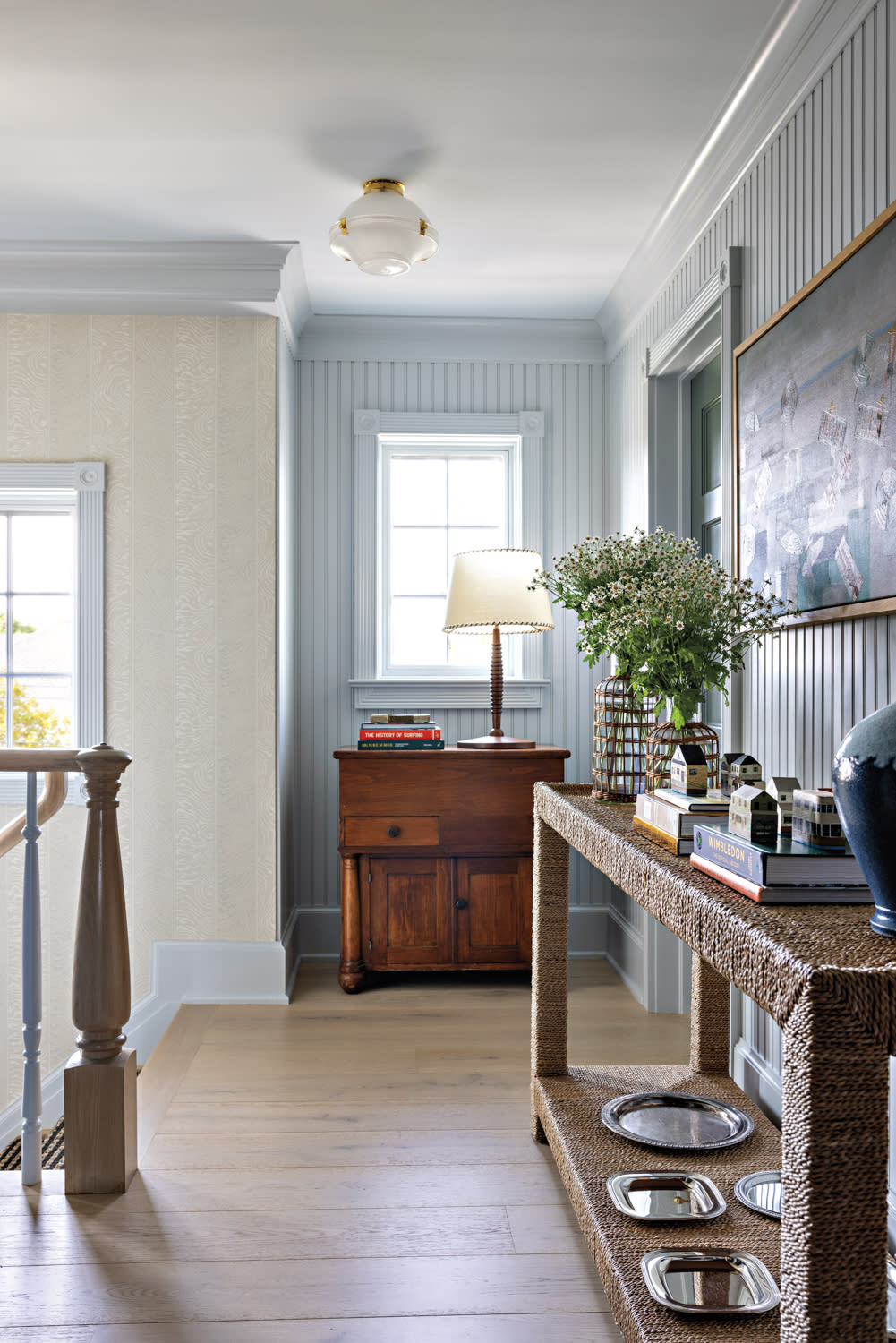 blue paneled wall behind a woven table in the entry