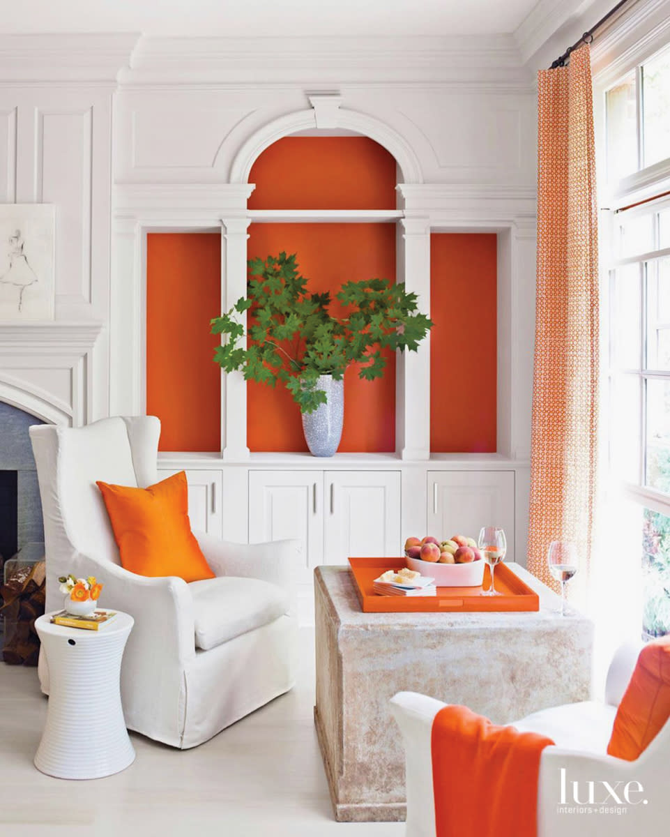 sitting area with white furniture and orange accents