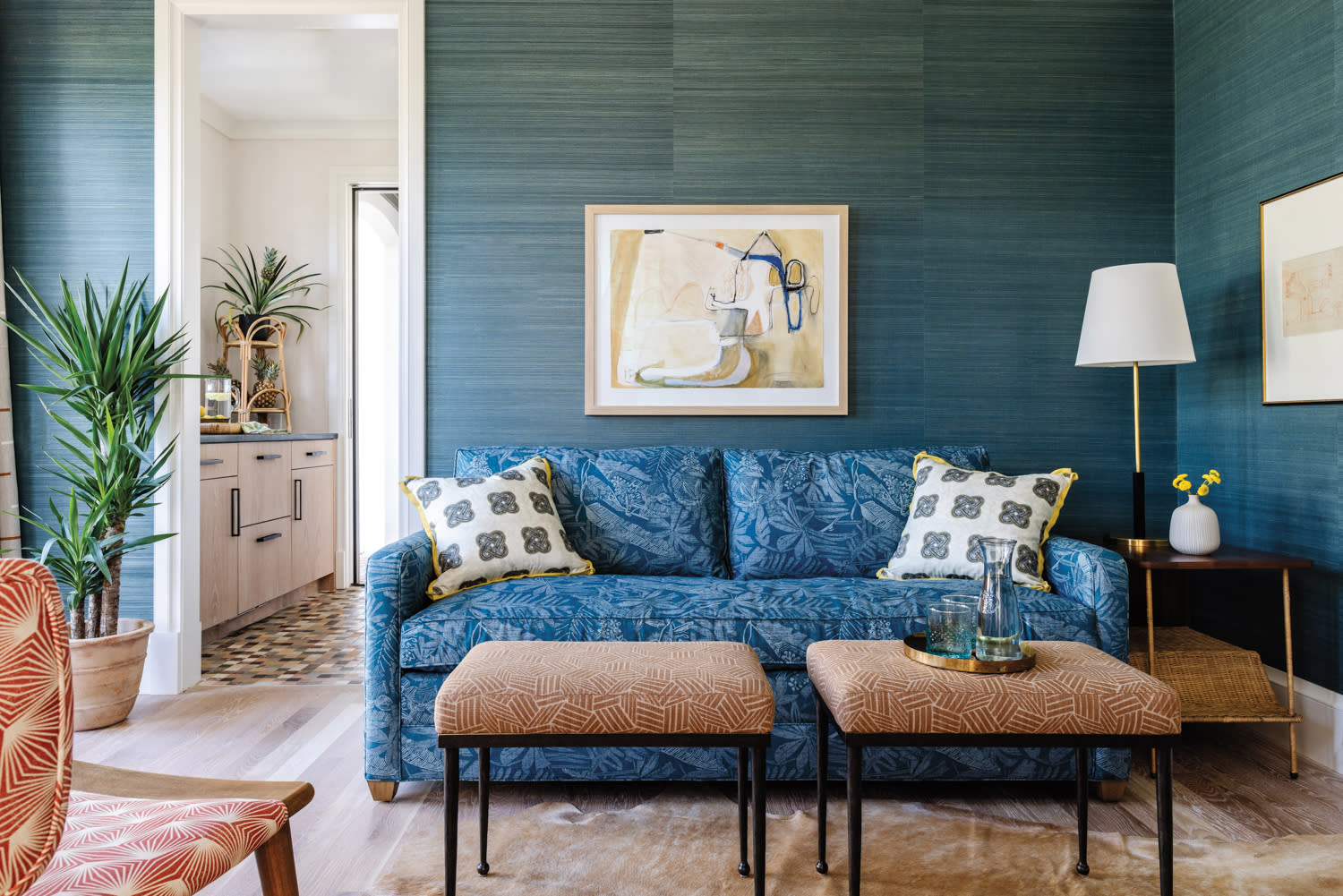 sitting room with teal wallcovering, teal sofa, pink benches and patterned pillows