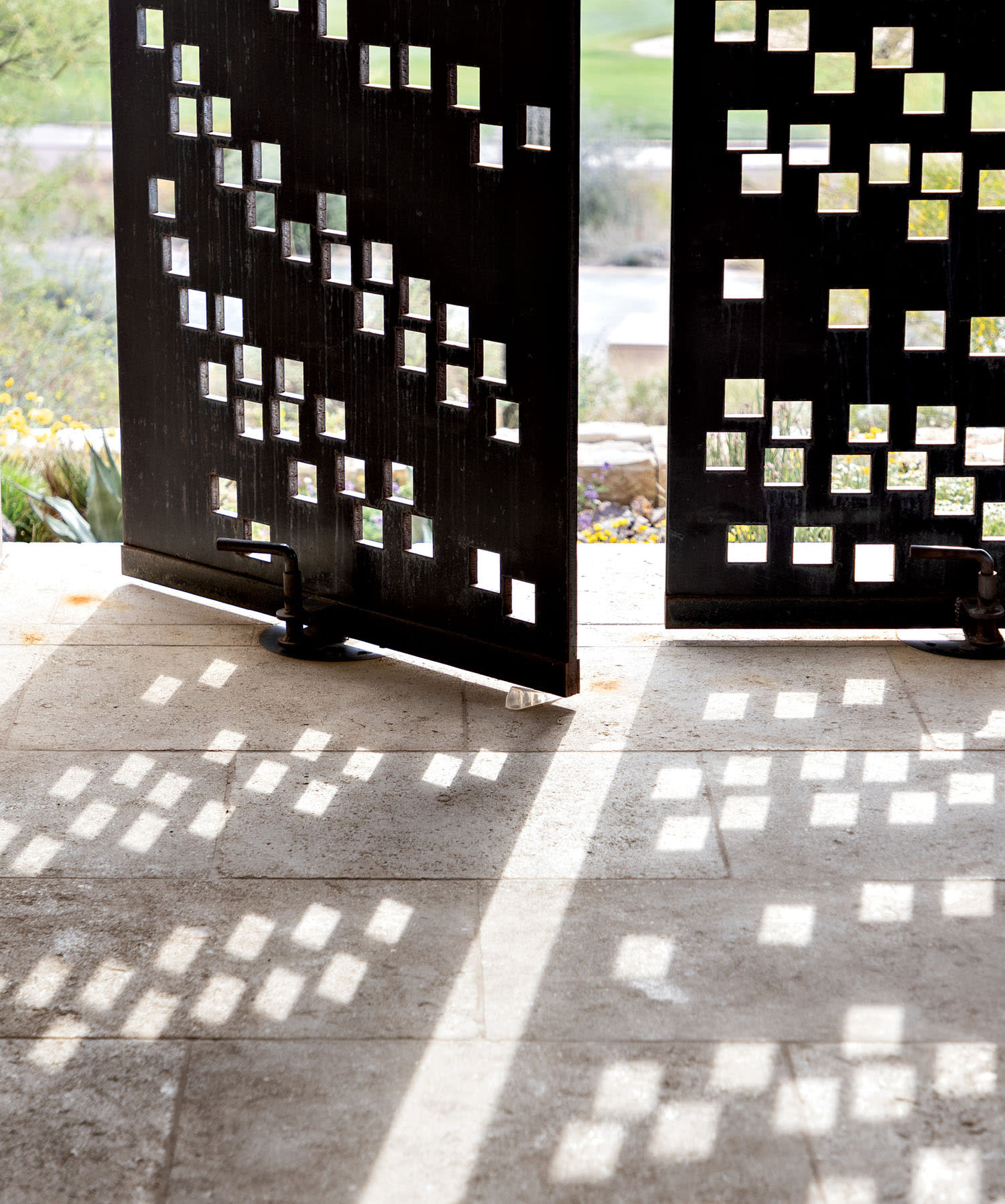 Steel panels on an outdoor patio let light in through perforated holes and by turning open and shut.
