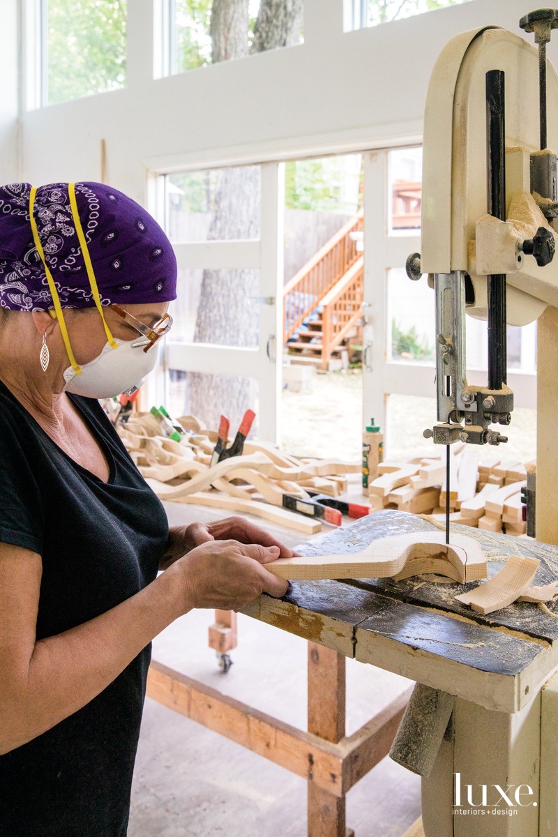 Pierucci holds a band saw to cut wood piece in studio