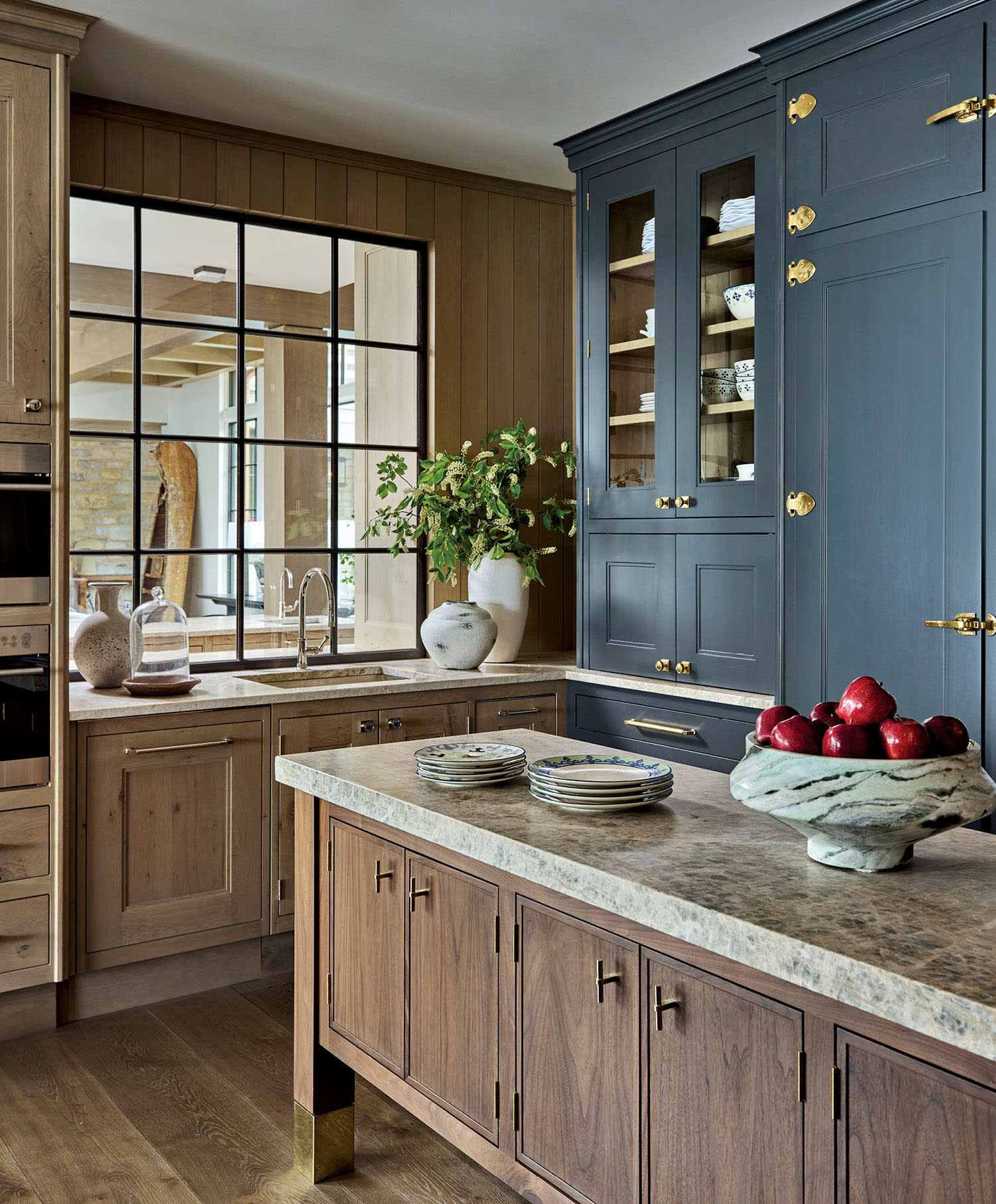 Elegant kitchen with wooden cabinets, marble countertops, and a large window.