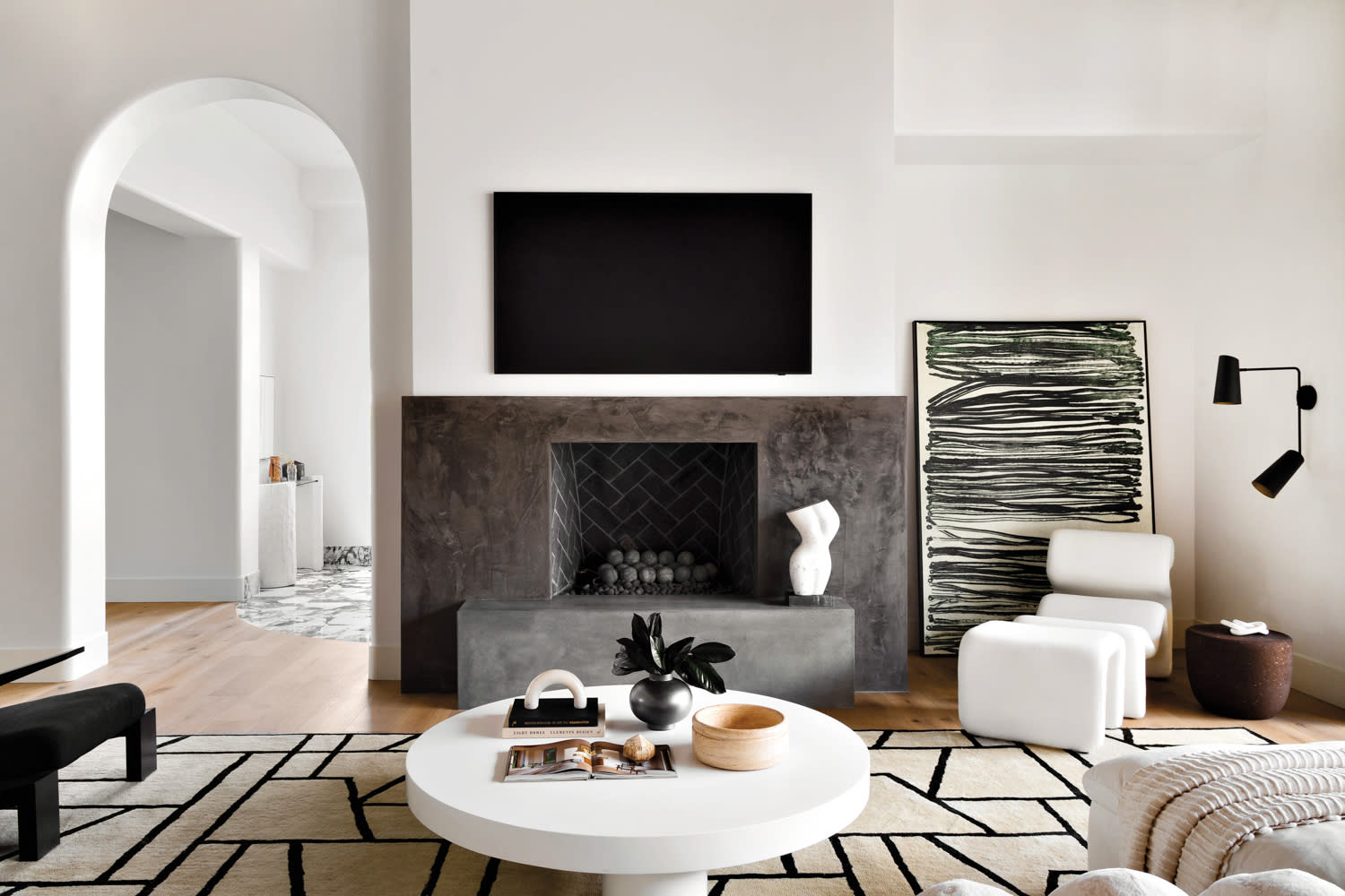 living room with a black fireplace, geometric rug, black-and-white artwork and coffee table by Kaitlyn Wolfe