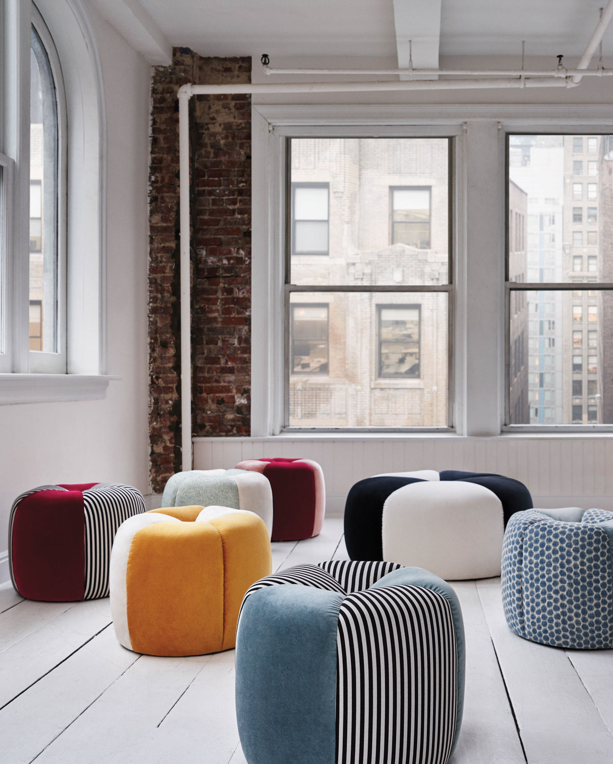 Multiple colorful ottomans by Rafael de Cárdenas for Mitchell Gold + Bob Williams in an empty loft