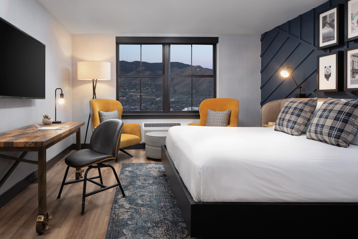 Hotel room with yellow chairs and black headboard wall.