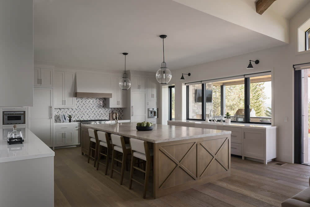 A modern kitchen showcasing European oak flooring, a large island and an expansive window, enhancing the room's brightness and openness.